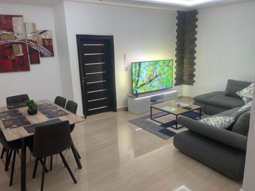 a living room with a couch and a table and a tv at RESIDENCE MH SERVICES Cotonou in Cotonou
