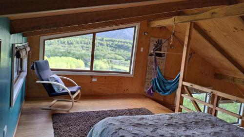 a bedroom with a bed and a large window at Refugio del río, a orillas del río Cochrane in Cochrane