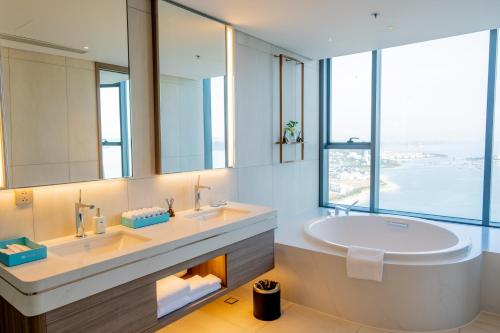 a bathroom with two sinks and a large mirror at A La Carte Ha Long Bay Managed by TASECO in Ha Long