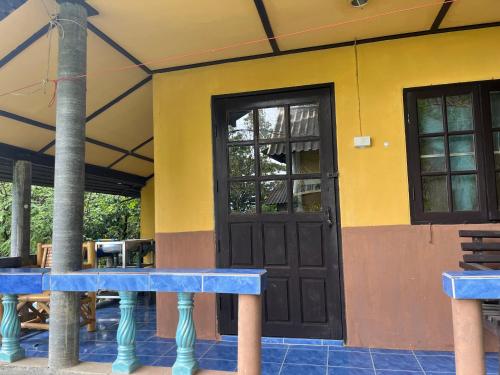 a yellow building with a black door and windows at Silver cliff room 15 in Than Sadet Beach