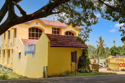 uma casa amarela com um telhado vermelho em OYO Flagship Sri Balaji Lodge Non Ac em Pollāchi