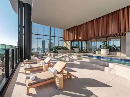 a pool with chaise lounges in a building at Above Broadbeach casino 1BRplus Study ocean-city views in Gold Coast