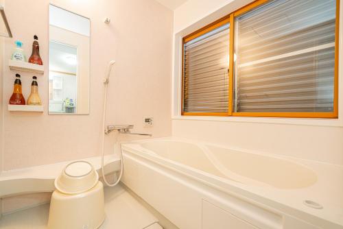 a white bathroom with a tub and a window at 団体歓迎ジョイサウンドカラオケ付き北軽井沢超大型貸別荘7寝室5浴室20人泊まれる in Karuizawa