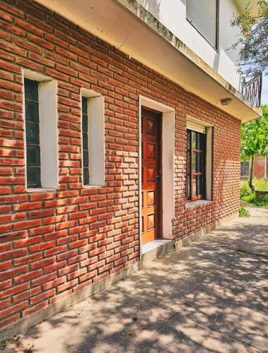 a brick building with a brown door and two windows at Con SEÑA previa, Alquiler de Sábado a Sábado, Fanuchito Dto PB Esquina, in San Clemente del Tuyú