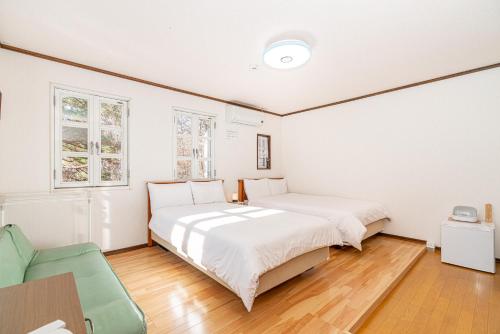 a white bedroom with two beds and a chair at 団体歓迎ジョイサウンドカラオケ付き北軽井沢超大型貸別荘7寝室5浴室20人泊まれる in Karuizawa