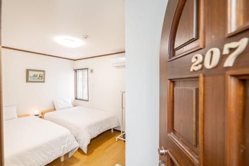 a room with two beds and a door at 団体歓迎ジョイサウンドカラオケ付き北軽井沢超大型貸別荘7寝室5浴室20人泊まれる in Karuizawa