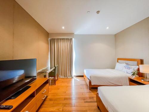 a hotel room with two beds and a flat screen tv at The Sea Luxury Nha Trang Apartment in Nha Trang