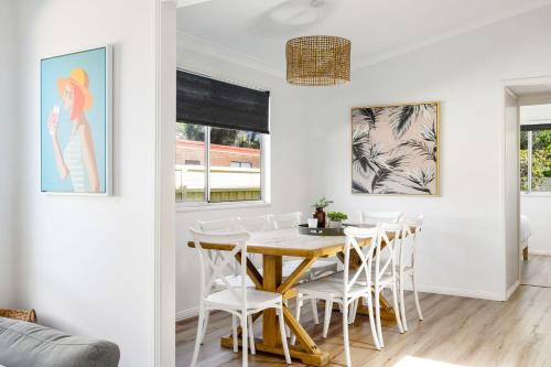 a dining room with a wooden table and white chairs at Golden Sands Pet Friendly 2 Mins Walk to Beach in Culburra Beach