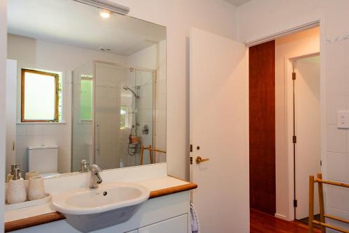 a white bathroom with a sink and a shower at Bali Escape, tropical gardens, close to 3 beaches! in Bowentown