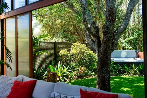 a white couch sitting next to a tree in a yard at Bali Escape, tropical gardens, close to 3 beaches! in Bowentown