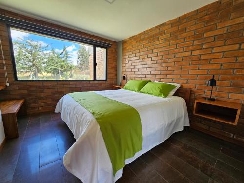 1 dormitorio con 1 cama grande y pared de ladrillo en El Chasqui Guest House, en Chasqui