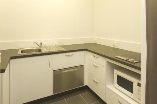 a kitchen with white cabinets and a sink at Glenmore Palms Motel in Rockhampton