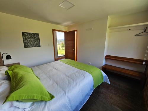 a bedroom with a bed with a green blanket on it at El Chasqui Guest House in Chasqui