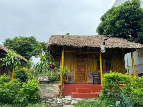 a small yellow house with a thatch roof at Ninh Binh Bamboo Farmstay in Ninh Binh