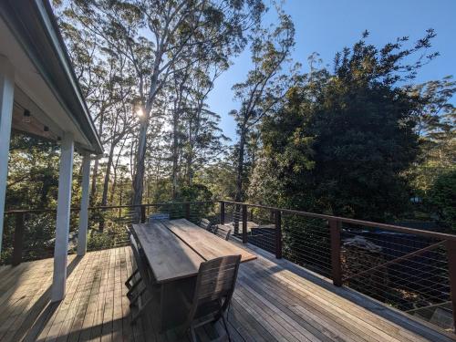 a wooden bench on a deck with trees in the background at Sanctuary Retreat in North Avoca
