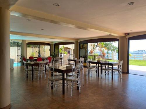 een eetkamer met tafels en stoelen en grote ramen bij Sierra Resort powered by Cocotel in Dauin