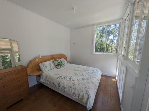 a bedroom with a bed and a dresser and two windows at Sanctuary Retreat in North Avoca