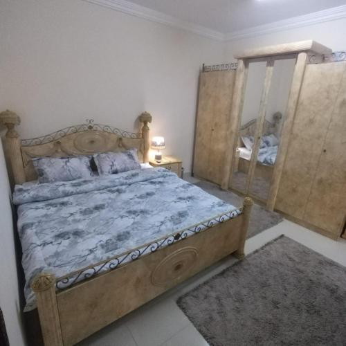 1 dormitorio con cama grande de madera y espejo en العين الهيلي مصباح بيت 9, en Al Ain