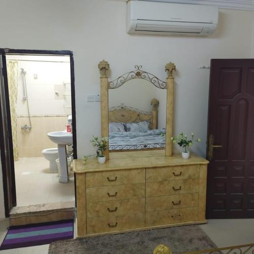 1 dormitorio con espejo y tocador de madera en العين الهيلي مصباح بيت 9, en Al Ain