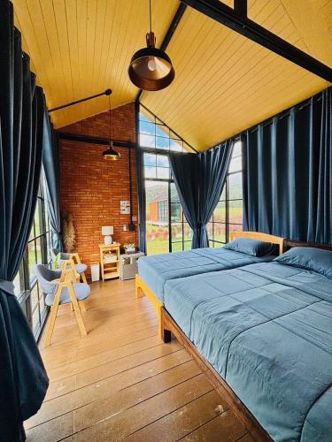 a bedroom with two beds in a room with blue drapes at The Maewin Coffee & Cottage Economy Family Room in Ban Huai Rin
