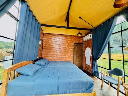 a bedroom with a bed in a room with windows at The Maewin Coffee & Cottage Economy Family Room in Ban Huai Rin