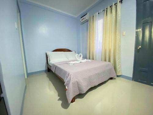 um quarto com uma cama num quarto azul em Althea Apartelle em Moalboal