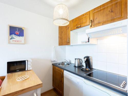 une petite cuisine avec un évier et un micro-ondes dans l'établissement Grand Appartement pour 6 avec Parking à Peyragudes - FR-1-695-43, à Germ