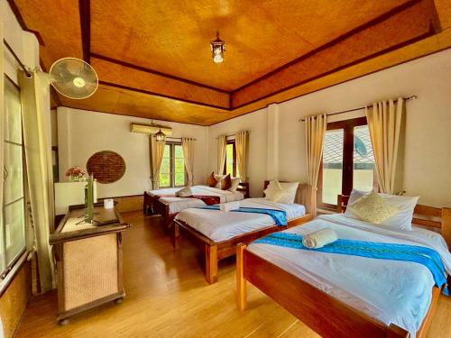 a bedroom with three beds in a room at Pai Love & Baan Chonphao Resort in Pai