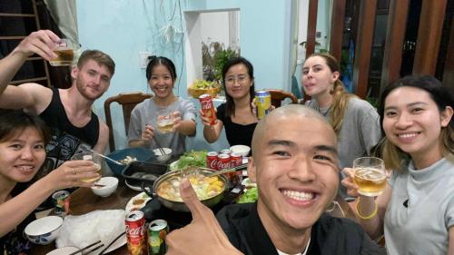 a group of people sitting around a table eating food at Laoxao Homestay in Hoi An