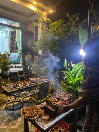a woman standing in front of a buffet of food at Laoxao Homestay in Hoi An