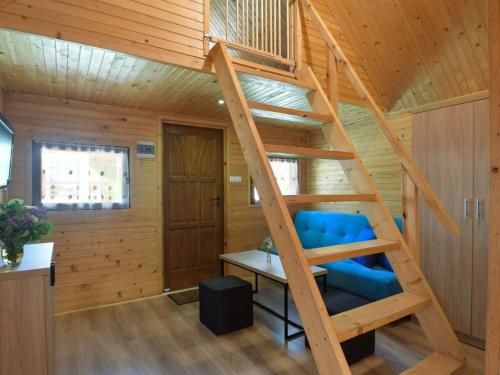 a wooden spiral staircase in a room with a blue chair at Cozy holiday cottages close to the beach, azy in Łazy