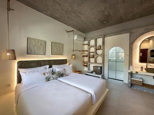 a bedroom with a large white bed and a bathroom at El Tropico Boutique Hotel in Kuta Lombok