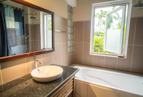 a bathroom with a sink and a tub and a window at Lagom Home in Hue