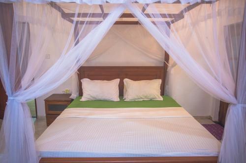 een slaapkamer met een hemelbed met witte gordijnen bij Relax Villa In Koggala in Habaraduwa Central