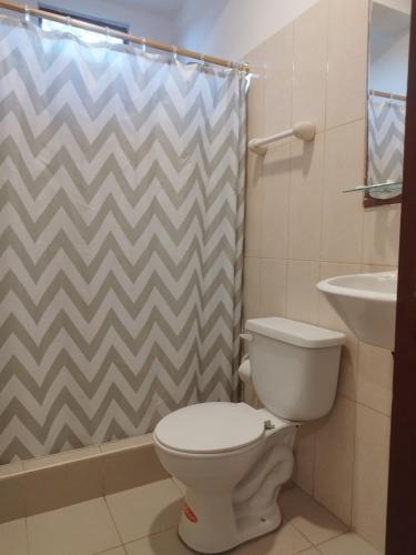 a bathroom with a toilet and a shower curtain at Palmendros Hosteria in Montañita
