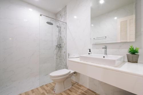 La salle de bains blanche est pourvue de toilettes et d'un lavabo. dans l'établissement Chao Wilai Residence I Naiyang Beach I HKT Airport, à Phuket