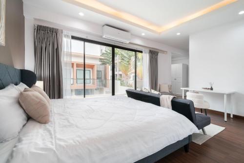 um quarto com uma cama grande e uma janela grande em Chao Wilai Residence I Naiyang Beach I HKT Airport em Phuket