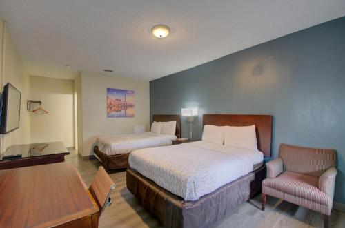 um quarto com 2 camas, uma mesa e uma cadeira em Budget Inn Falls Church em Falls Church