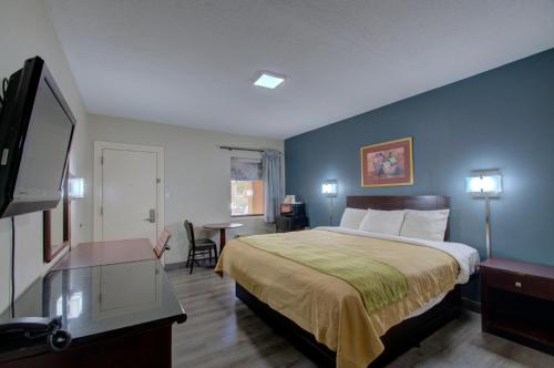 a hotel room with a bed and a flat screen tv at Budget Inn Falls Church in Falls Church