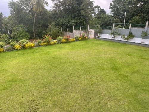 a yard with green grass and a fence and flowers at Kapaliya Unawatuna in Unawatuna