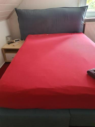 a red bed with a black pillow and a red blanket at Muller-Luxus-Hotel-Warburg in Warburg