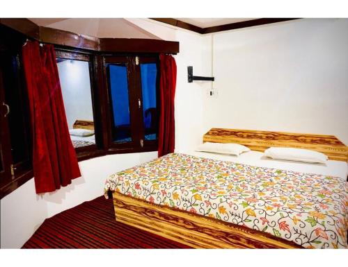 a bedroom with a bed and two windows at Snow Peak Guest House, Pahalgam in Pahalgām