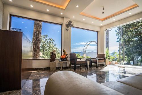 a living room with a large window and a couch at The Golden Sunrise Hotel in Nainital