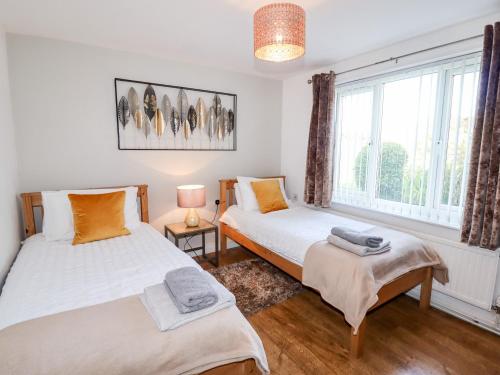 a bedroom with two beds and a window at The Flat At Brwyn in Holywell