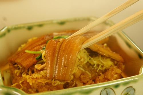 a pair of wooden chopsticks holding a dish of food at Kikunoya in Miyajima