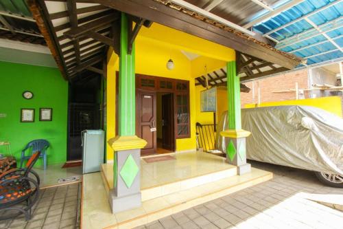 a yellow and green house with a covered porch at Kampung Osing Inn in Giri