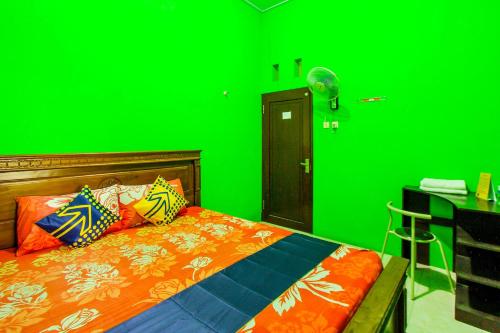 a green bedroom with a bed and a green wall at Kampung Osing Inn in Giri
