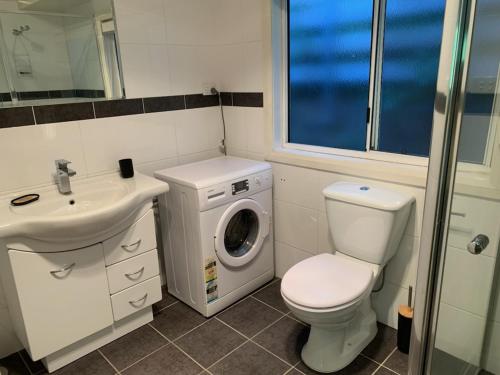 a bathroom with a toilet sink and a washing machine at Very Comfortable Granny Flat in Yass