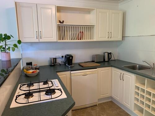 a kitchen with white cabinets and a stove top oven at Very Comfortable Granny Flat in Yass