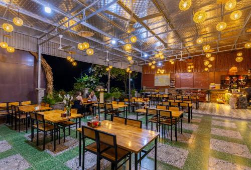 een restaurant met houten tafels, stoelen en verlichting bij Green Homestay in Cat Ba